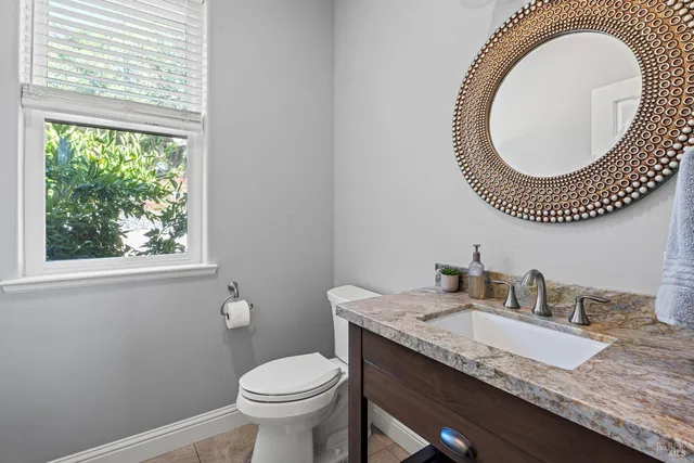 a bathroom with a granite countertop toilet a sink and a window
