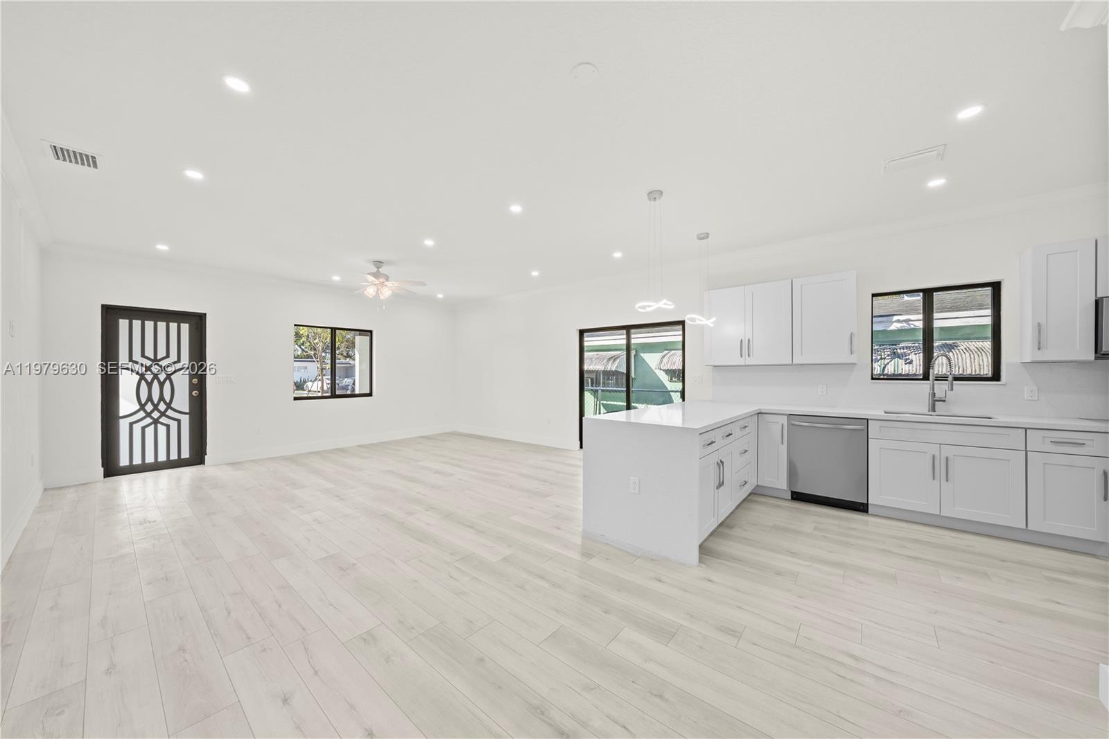 1735 Northwest 84th Street Miami, FL 33147 - Photo 7 of 26 a large white kitchen with cabinets and wooden floor