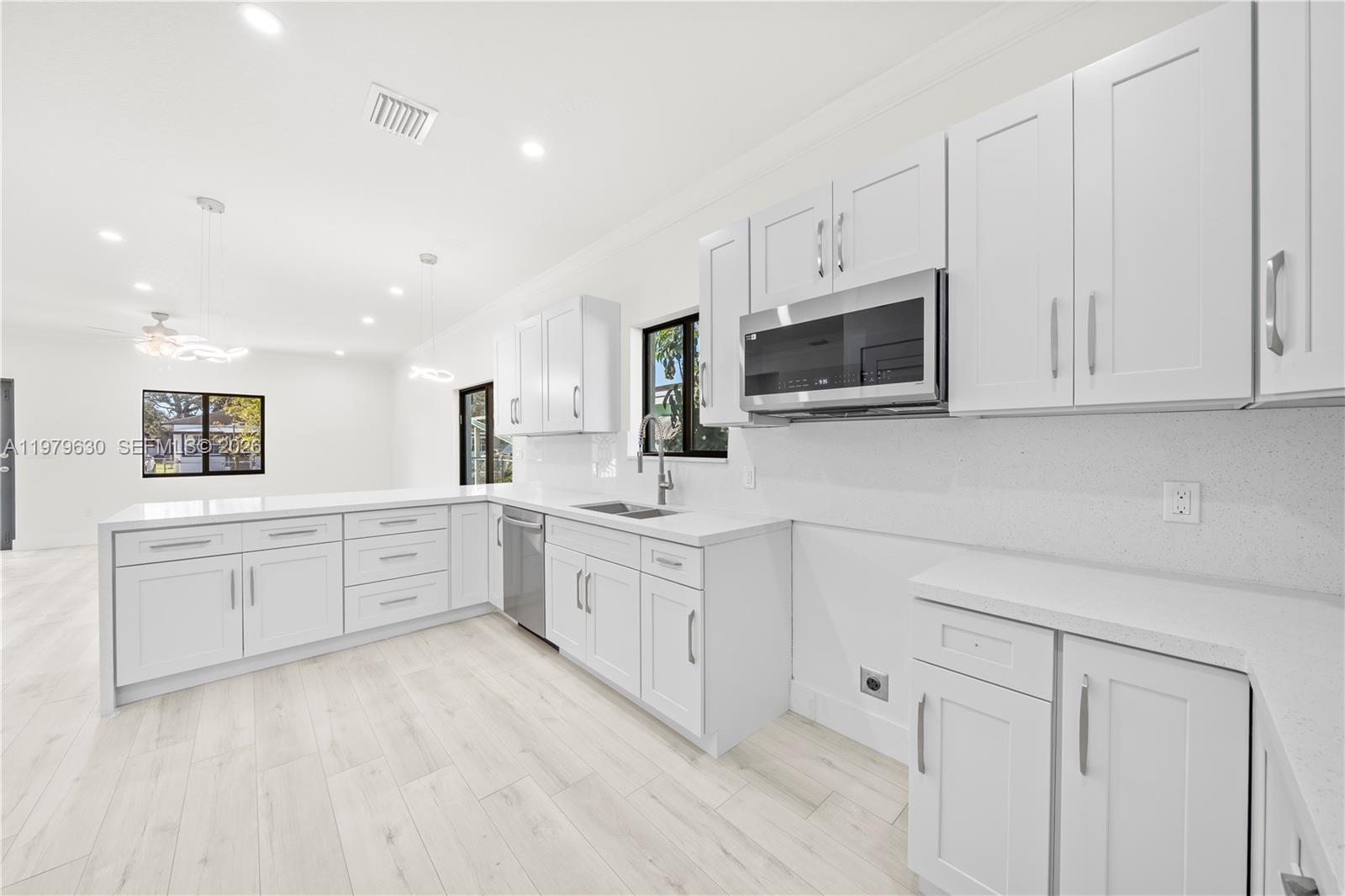 1735 Northwest 84th Street Miami, FL 33147 - Photo 9 of 26 a large white kitchen with stainless steel appliances granite countertop a stove a sink a microwave and cabinets