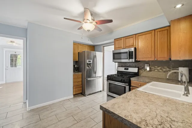 a kitchen with granite countertop a refrigerator oven a sink dishwasher and wooden cabinets