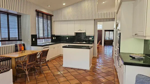 a kitchen with granite countertop a stove a sink a counter space and cabinets