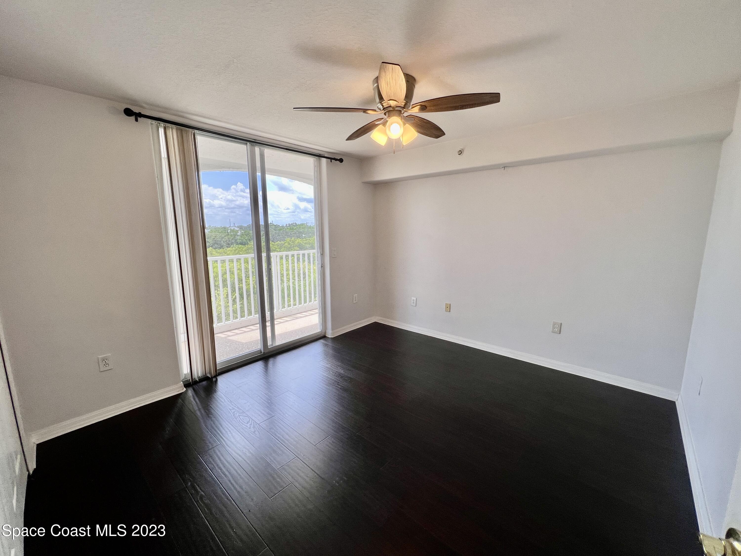 800 Del Rio Way, Unit 402 Merritt Island, FL 32953 - Photo 11 of 24 an empty room with wooden floor fan and windows
