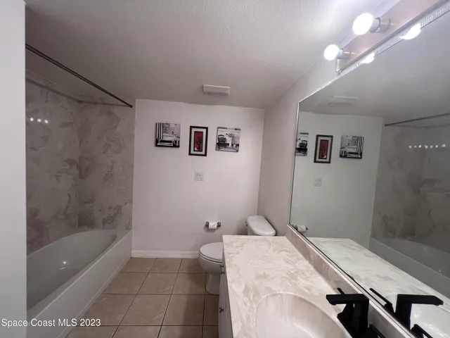 a bathroom with a granite countertop sink a toilet and shower