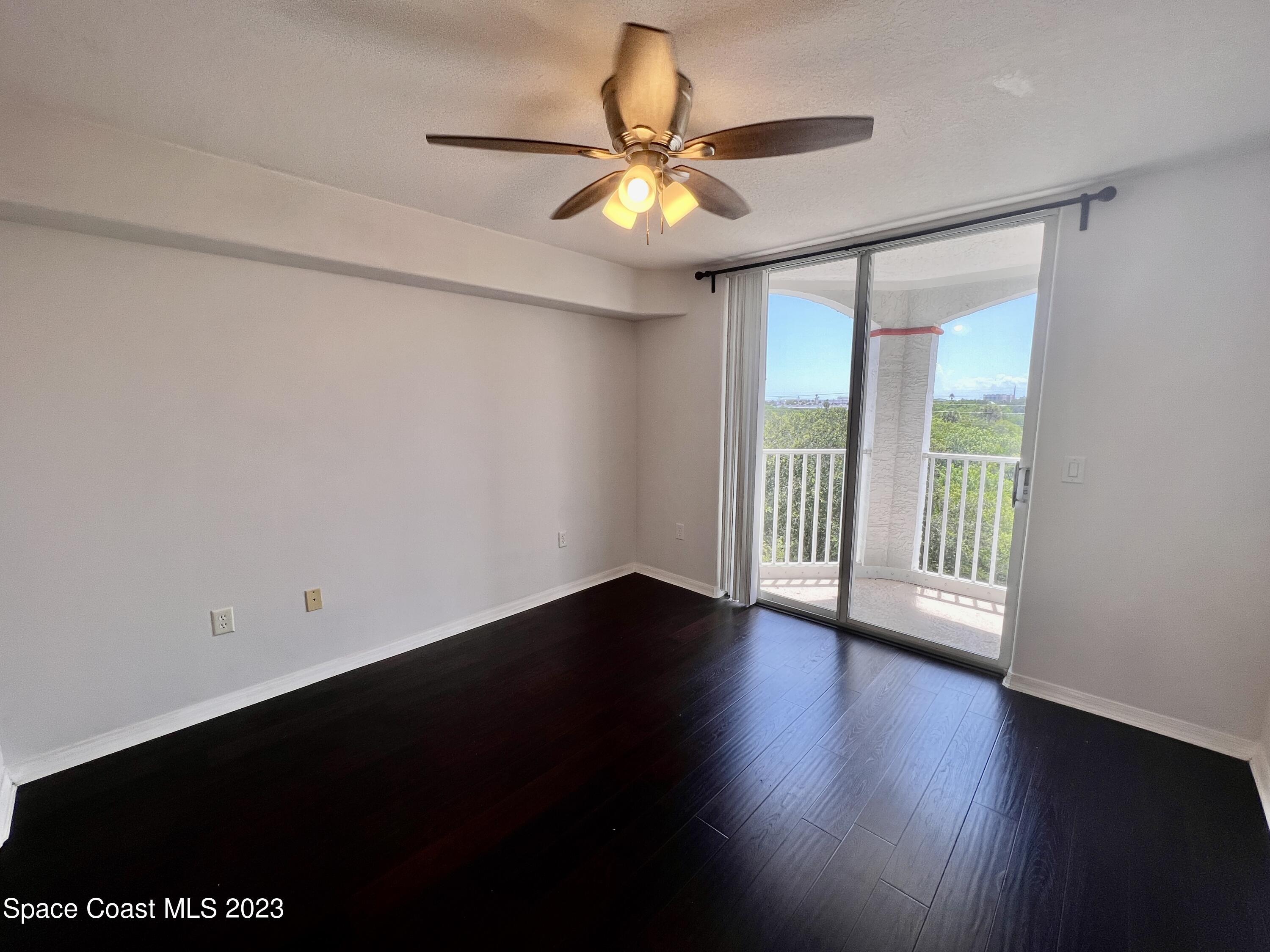 800 Del Rio Way, Unit 402 Merritt Island, FL 32953 - Photo 13 of 24 a view of an empty room with wooden floor and a window