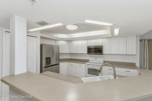 a kitchen with granite countertop white cabinets and stainless steel appliances