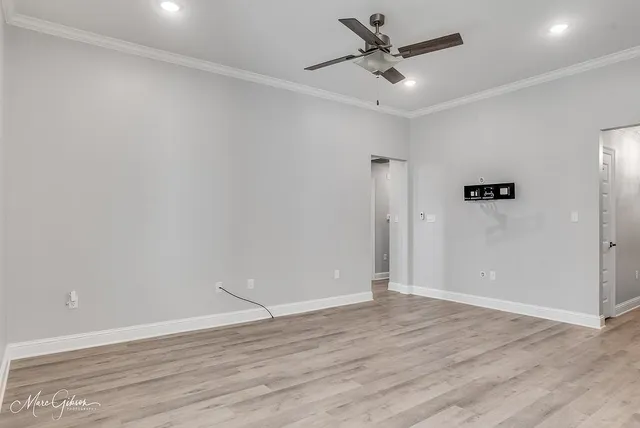 an empty room with wooden floor and ceiling fan