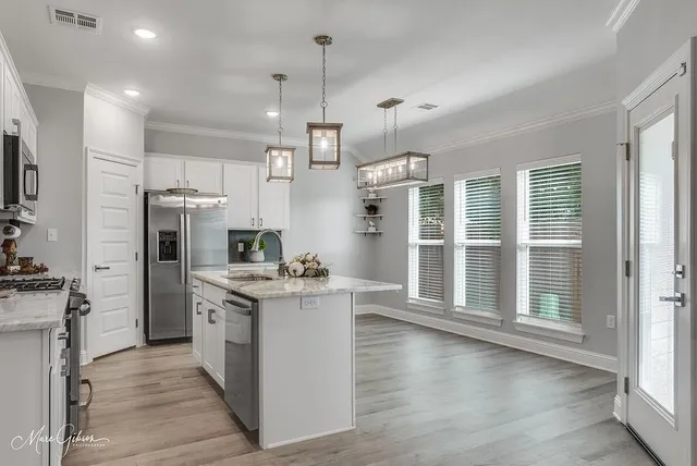 a kitchen with stainless steel appliances granite countertop a stove a refrigerator a sink dishwasher and a oven with wooden floor