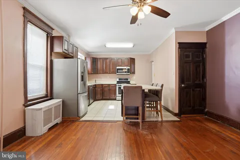a kitchen with stainless steel appliances granite countertop a refrigerator a stove top oven a chimney cabinets and wooden floor