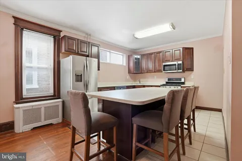 a kitchen with stainless steel appliances granite countertop a table chairs and a refrigerator