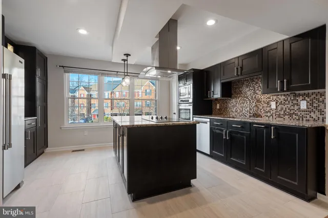 a kitchen with stainless steel appliances kitchen island granite countertop a refrigerator and a stove top oven