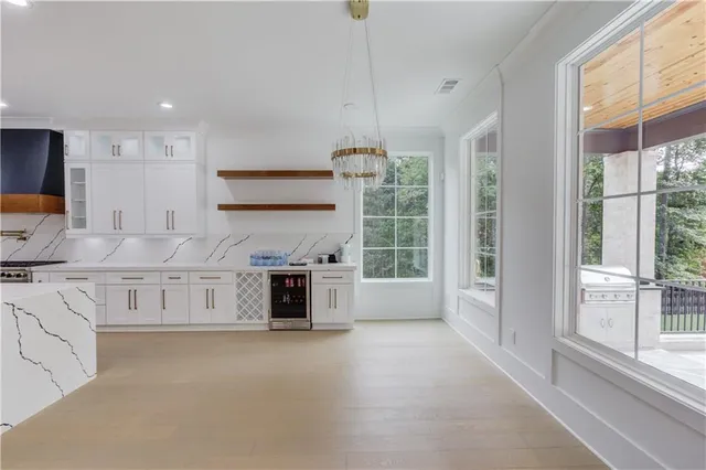 a large white kitchen with granite countertop a stove a sink a window and white cabinets