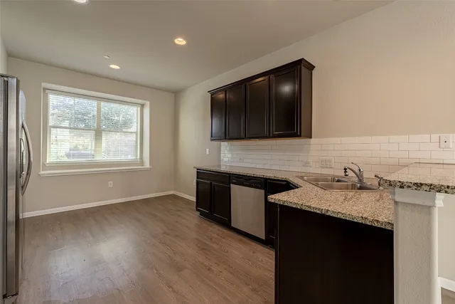 a kitchen with granite countertop stainless steel appliances a sink stove and cabinets