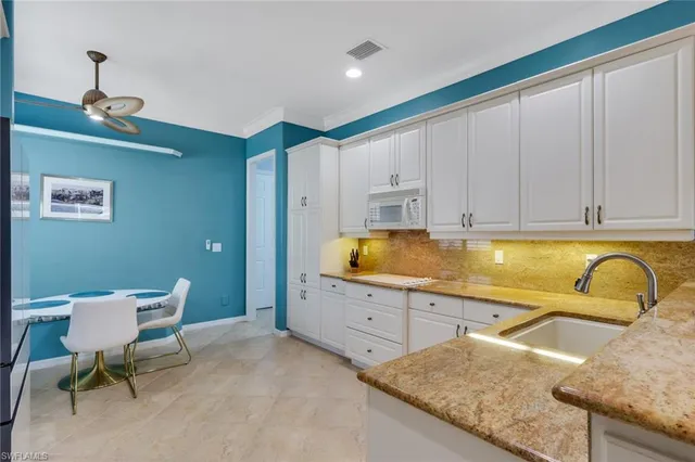 a kitchen with granite countertop a sink and white cabinets