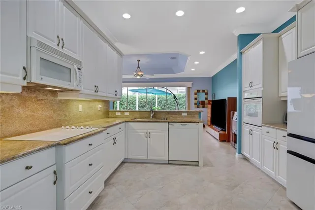 a kitchen with granite countertop white cabinets and refrigerator