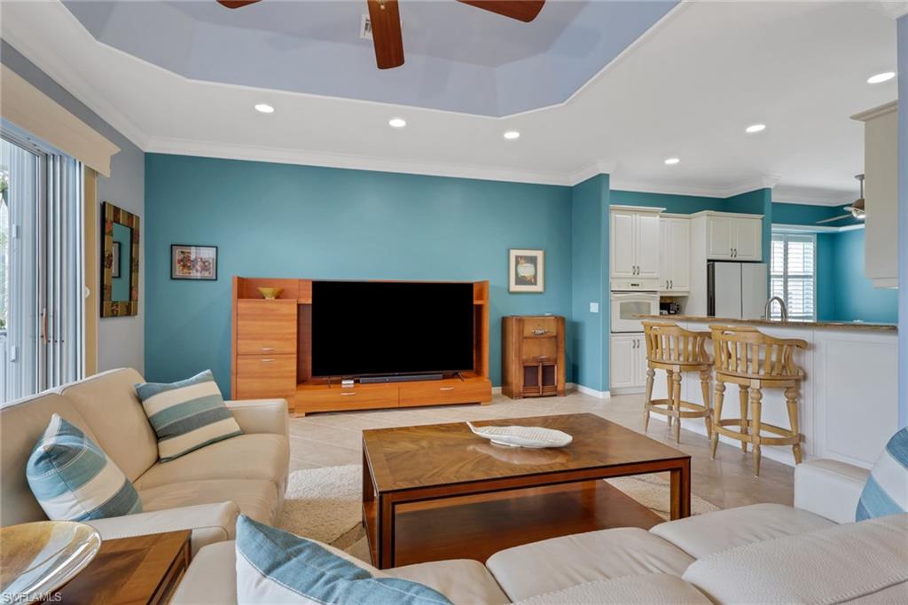 9348 Sun River Way Estero, FL 33928 - Photo 22 of 50 Living area featuring a ceiling fan, crown molding, recessed lighting, light tile patterned flooring, and a tray ceiling