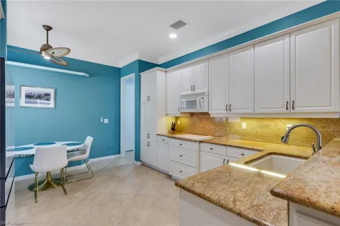 a kitchen with granite countertop a sink and white cabinets