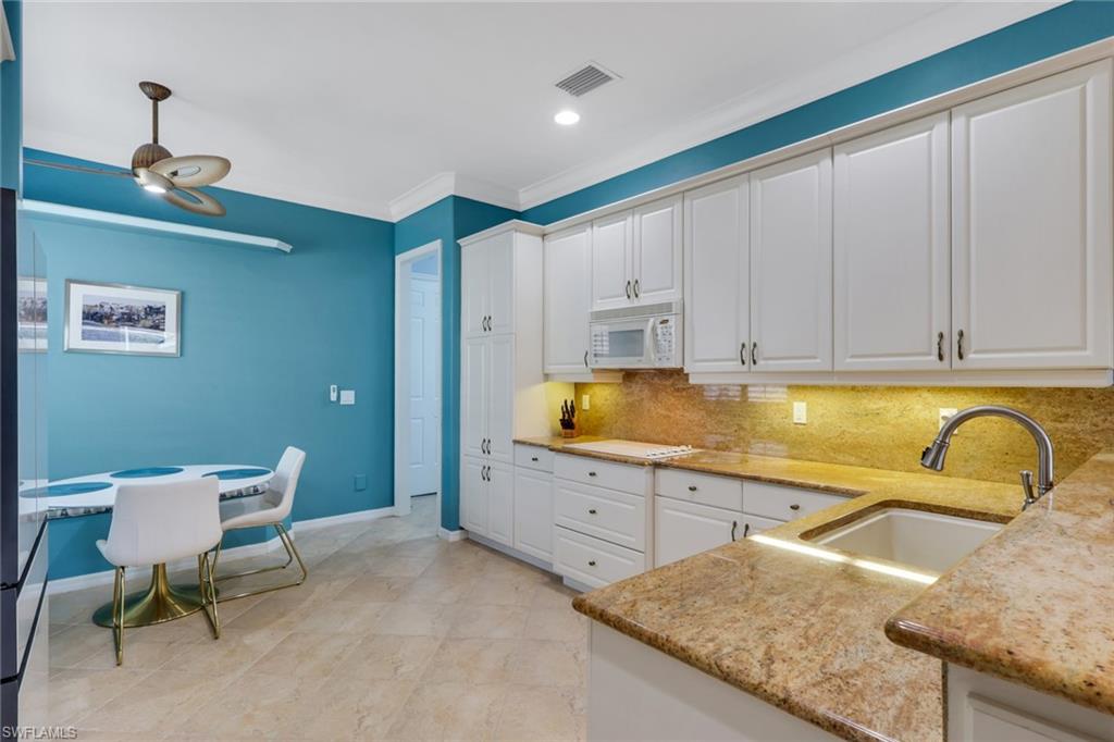 9348 Sun River Way Estero, FL 33928 - Photo 24 of 50 Kitchen with white cabinetry, light stone countertops, white appliances, ornamental molding, and decorative backsplash
