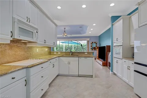 a kitchen with granite countertop white cabinets and refrigerator