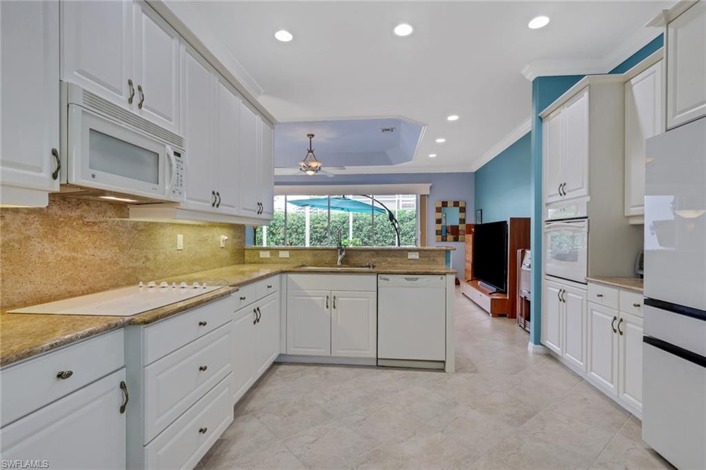 9348 Sun River Way Estero, FL 33928 - Photo 25 of 50 Kitchen with recessed lighting, crown molding, white appliances, white cabinetry, and light stone countertops