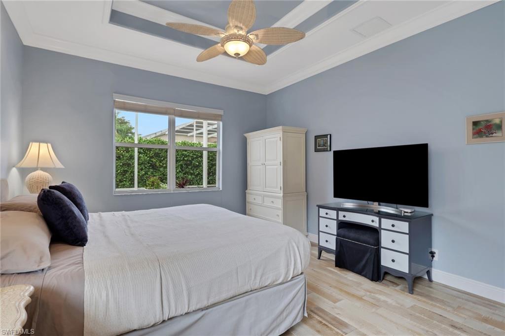 9348 Sun River Way Estero, FL 33928 - Photo 28 of 50 Bedroom featuring light wood-style floors, ornamental molding, a ceiling fan, and a tray ceiling