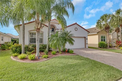 a front view of a house with a yard and palm trees