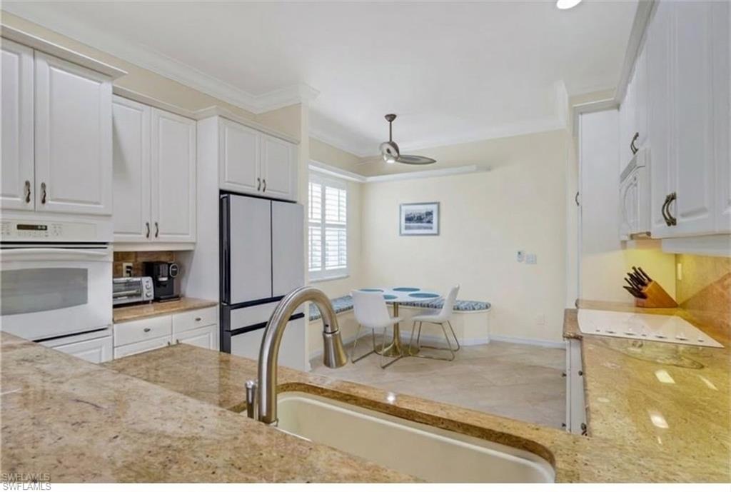 9348 Sun River Way Estero, FL 33928 - Photo 8 of 50 Kitchen featuring white appliances, white cabinets, light stone counters, ornamental molding, and a ceiling fan