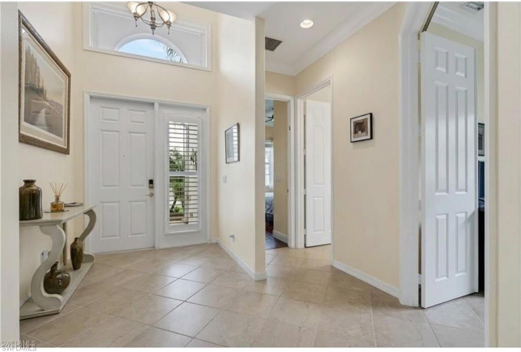 9348 Sun River Way Estero, FL 33928 - Photo 10 of 50 Foyer entrance with hanging lights, crown molding, and light tile patterned flooring