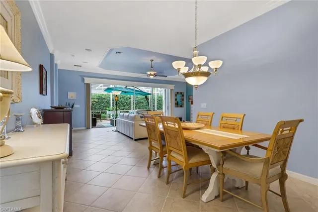 a view of a dining room with furniture a chandelier and large windows