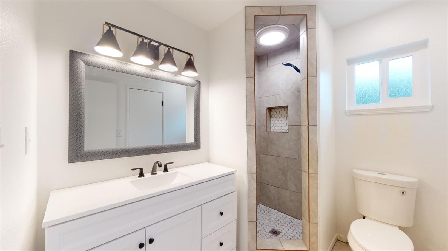 1237 De Cesari Avenue Madera, CA 93637 - Photo 18 of 24 a bathroom with a toilet a sink a light fixture and a mirror