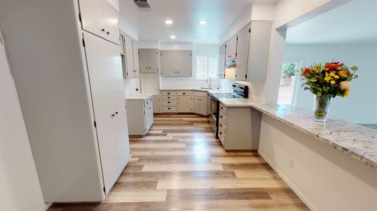 1237 De Cesari Avenue Madera, CA 93637 - Photo 6 of 24 a view of a kitchen with kitchen island stainless steel appliances sink refrigerator and microwave