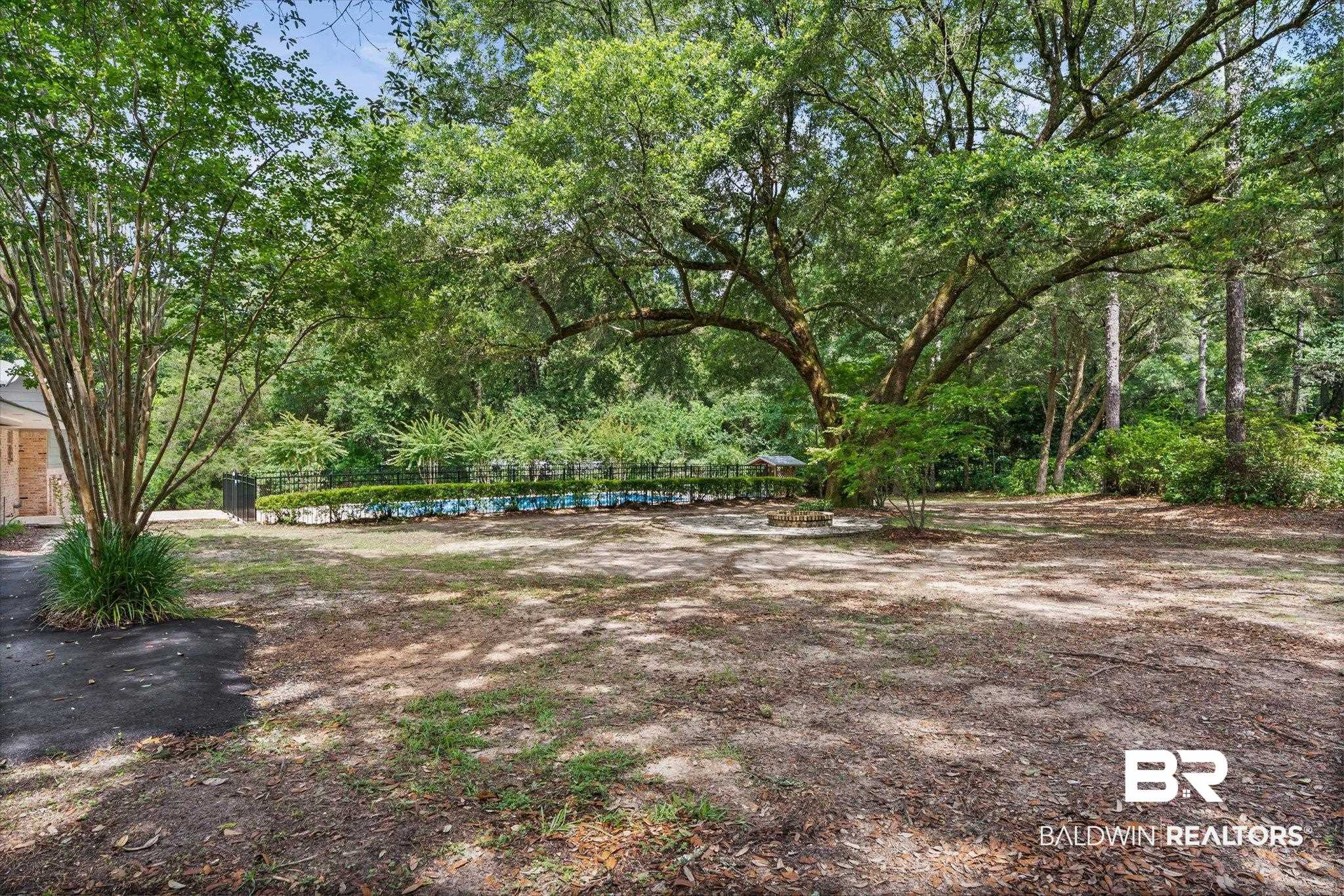 8301 Fordham Road Mobile, AL 36619 - Photo 36 of 57 Expansive tree-lined property featuring a visible in-ground swimming pool with a black iron fence