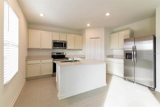 a kitchen with granite countertop a refrigerator and a stove top oven