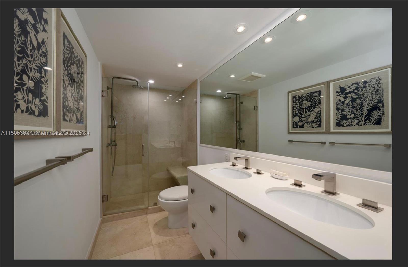 1111 Crandon Boulevard, Unit C406 Key Biscayne, FL 33149 - Photo 3 of 6 a bathroom with a double vanity sink a toilet a mirror and shower