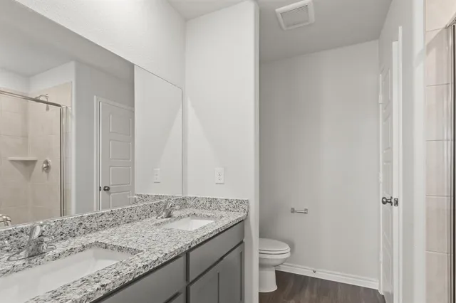 a bathroom with a granite countertop sink and a toilet