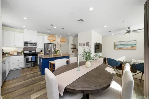 a living room with stainless steel appliances furniture a dining table and kitchen view