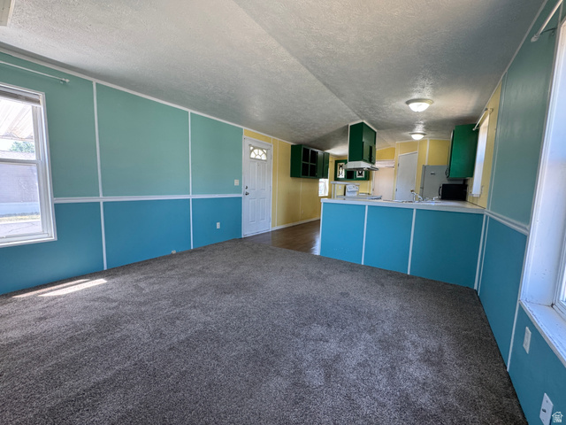 2491 Highway 89, Unit 315 Pleasant View, UT 84404 - Photo 28 of 34 Spacious living area featuring grey carpeting, two-tone wall paneling, and an open-concept layout to the kitchen