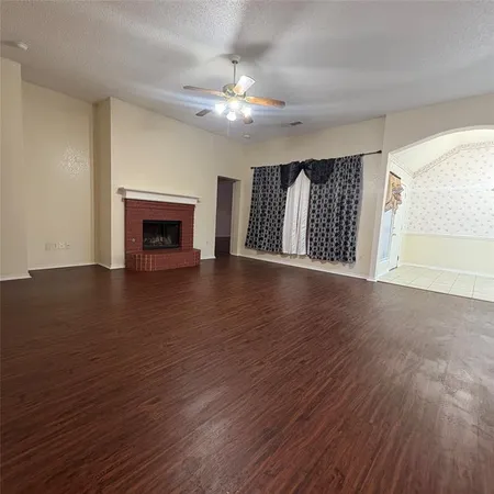 a view of an empty room with wooden floor fireplace and a window
