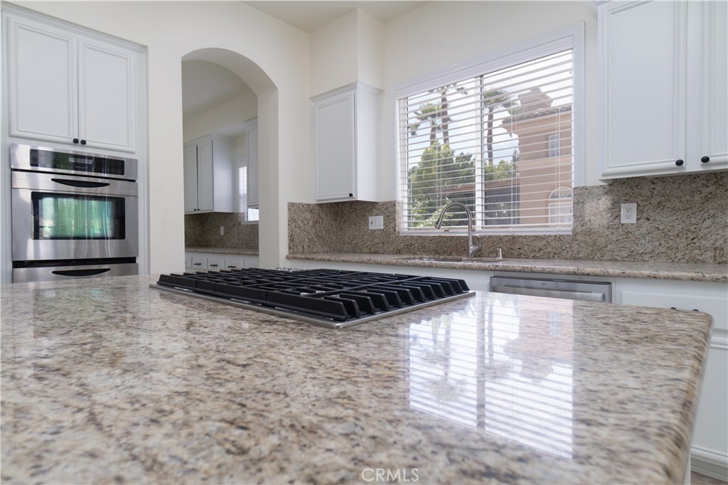 583 Ruth Circle Corona, CA 92879 - Photo 27 of 74 a kitchen with granite countertop a stove and a white cabinets