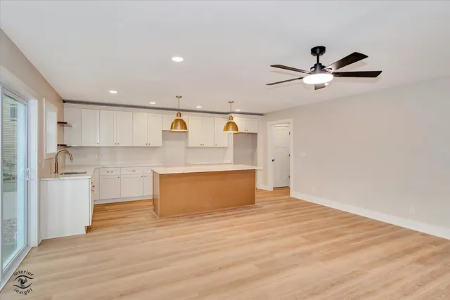 a large kitchen with stainless steel appliances a large counter top a stove a refrigerator and white cabinets