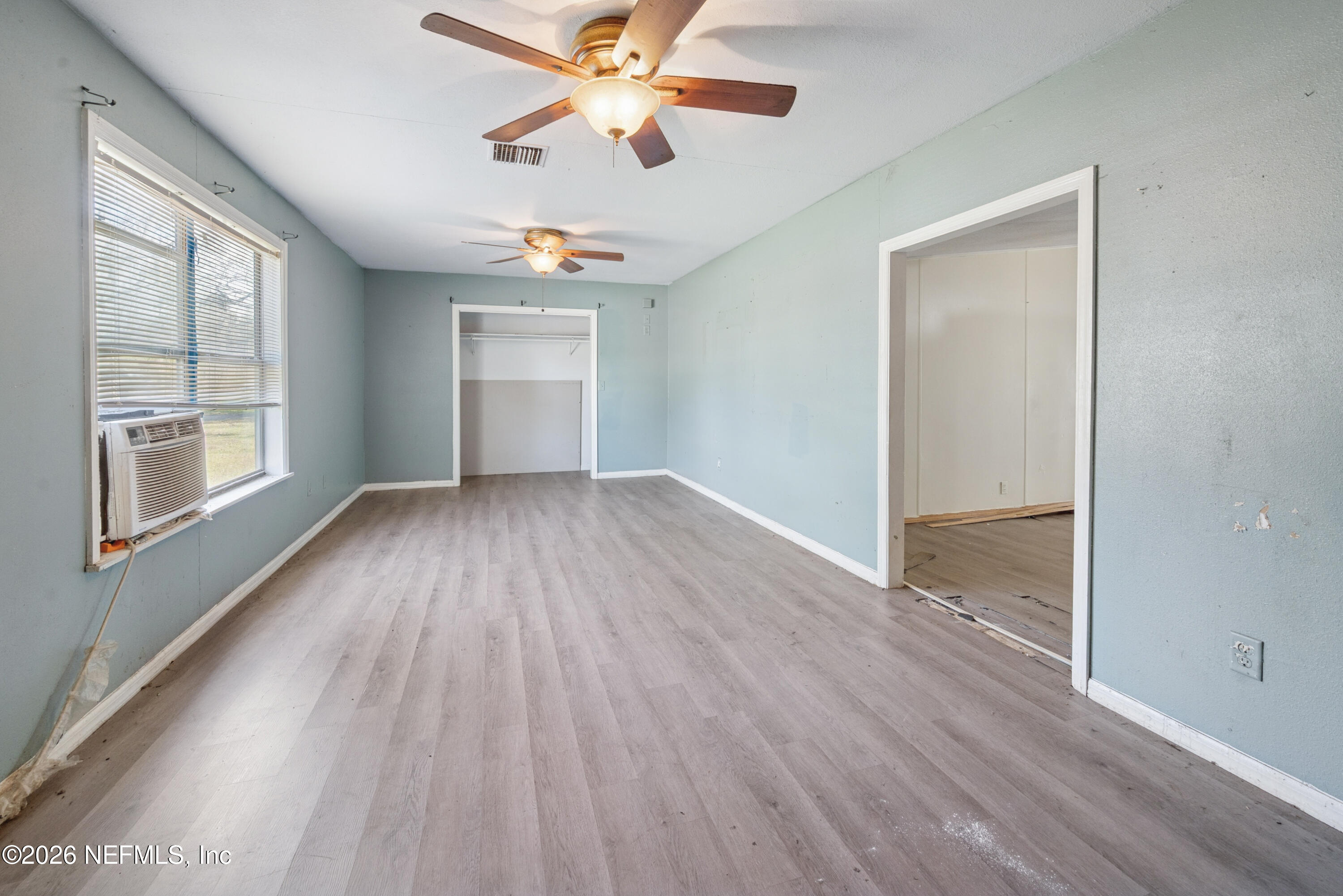 9860 State Rte 100 Starke, FL 32091 - Photo 7 of 24 an empty room with wooden floor chandelier fan and windows