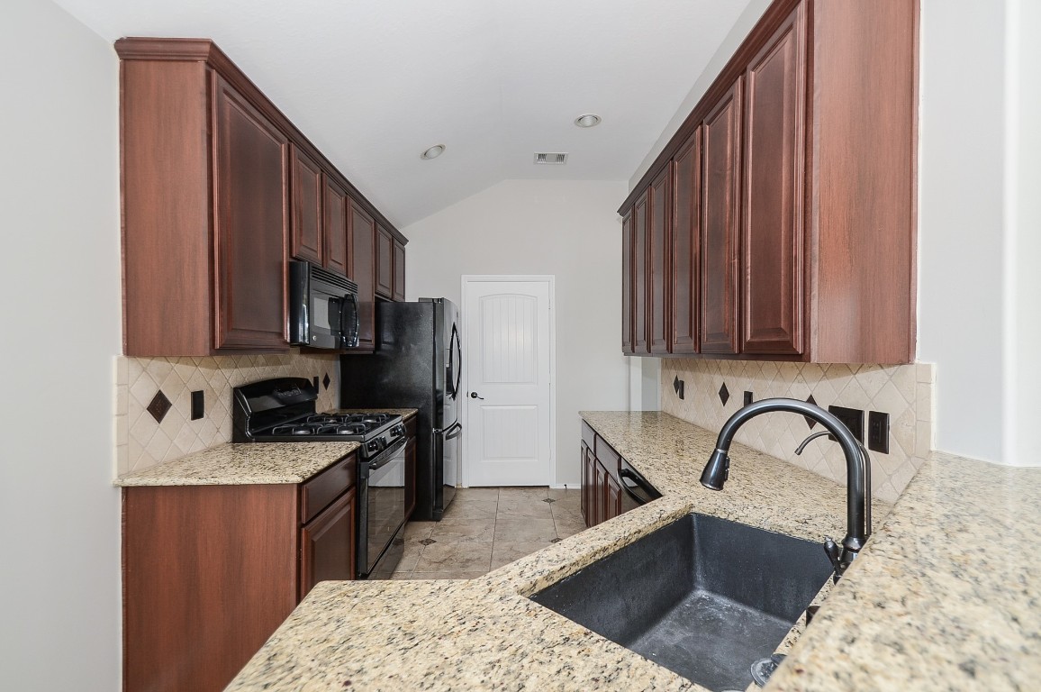 2646 Leopard Court Katy, TX 77449 - Photo 14 of 32 a kitchen with stainless steel appliances granite countertop a stove a sink dishwasher and cabinets with wooden floor