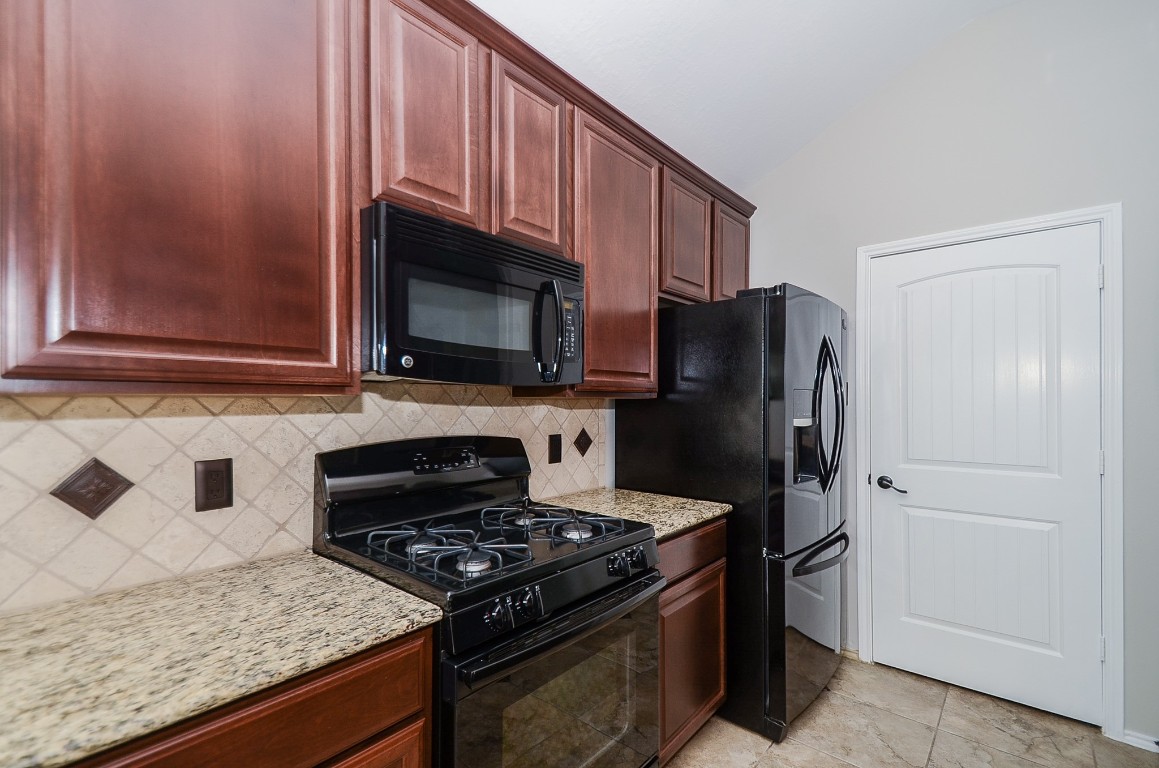 2646 Leopard Court Katy, TX 77449 - Photo 15 of 32 a kitchen with granite countertop wooden cabinets and stainless steel appliances