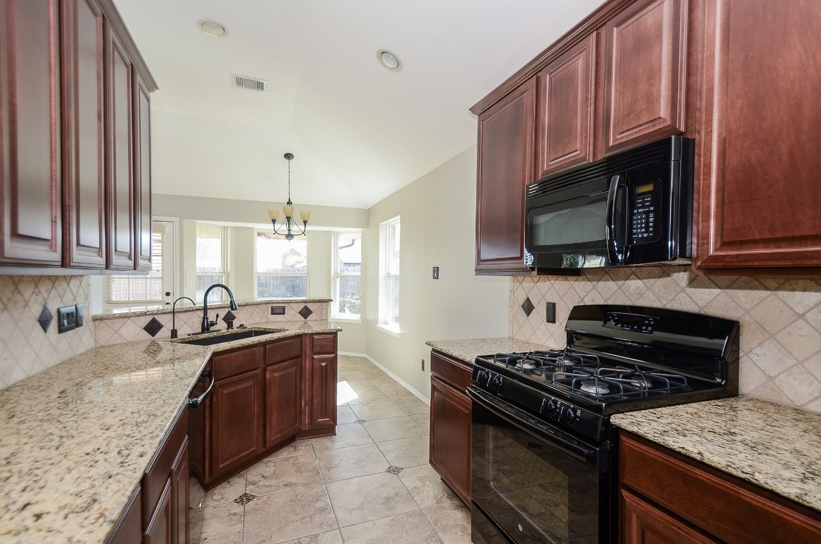 2646 Leopard Court Katy, TX 77449 - Photo 16 of 32 a kitchen with granite countertop a sink dishwasher stove and cabinets with wooden floor