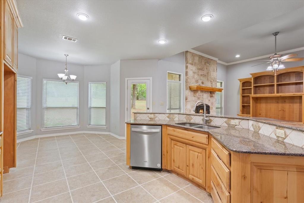 140 Oak Ridge Loop Whitney, TX 76692 - Photo 13 of 40 The kitchen features wooden cabinetry, granite countertops, and stainless steel appliances, with tile flooring extending into the dining area
