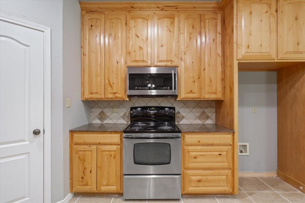 140 Oak Ridge Loop Whitney, TX 76692 - Photo 16 of 40 Kitchen featuring light wood cabinetry, stainless steel oven and microwave, granite-look countertops, and a tile backsplash with diamond accents