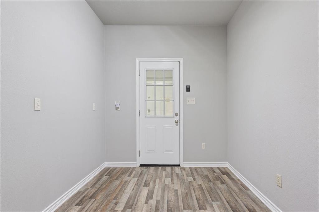 140 Oak Ridge Loop Whitney, TX 76692 - Photo 19 of 40 This room features light grey walls, wood-look flooring, and a white door with multiple glass panes
