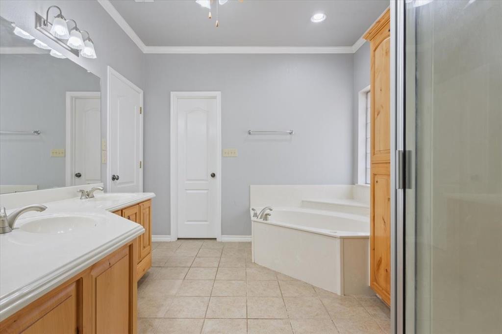 140 Oak Ridge Loop Whitney, TX 76692 - Photo 22 of 40 The bathroom features a double vanity with light wood cabinetry, a built-in bathtub, and a shower enclosure