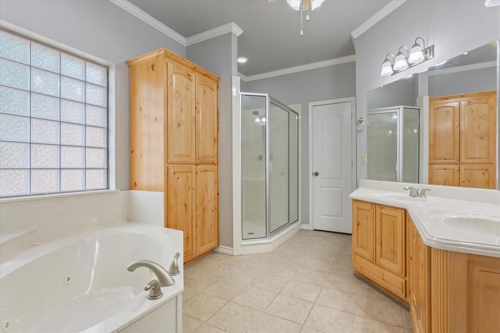 140 Oak Ridge Loop Whitney, TX 76692 - Photo 24 of 40 This bathroom features a soaking tub with brushed nickel fixtures, a glass-enclosed shower, and a double vanity with light wood cabinetry and white countertops