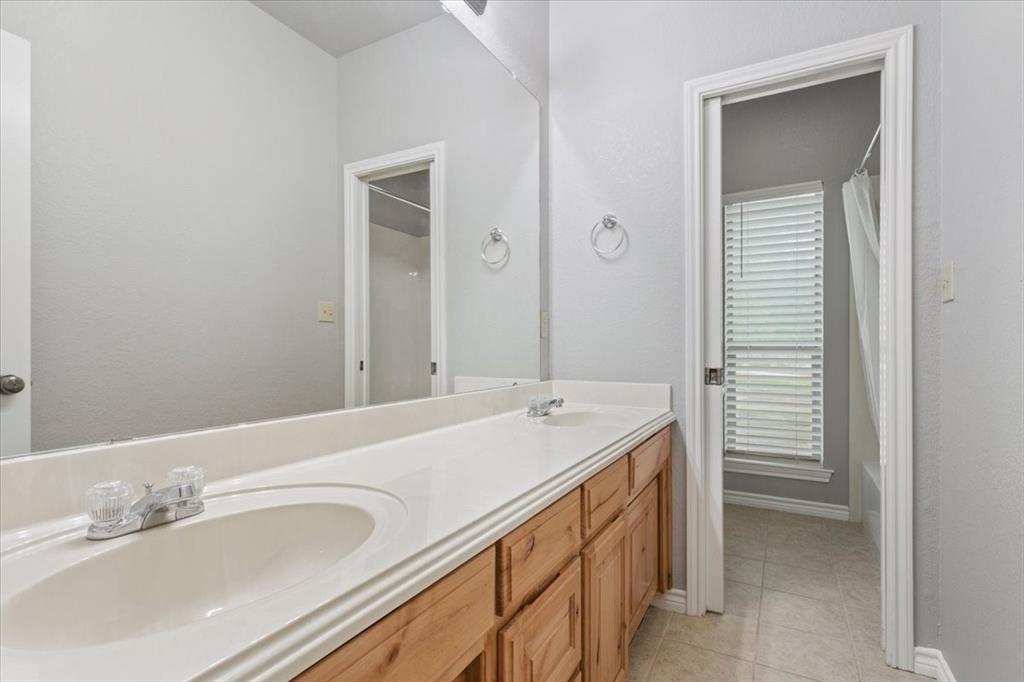140 Oak Ridge Loop Whitney, TX 76692 - Photo 30 of 40 Bathroom vanity with dual sinks, light wood cabinetry, and a large mirror