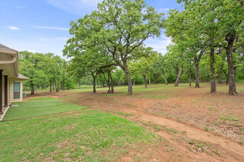 140 Oak Ridge Loop Whitney, TX 76692 - Photo 35 of 40 The property features an extensive outdoor area with a lawn, mature trees, and a dirt path